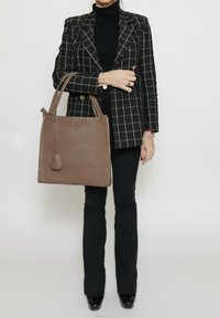 Bruine leren tote bag met een minimalistisch ontwerp, vlakke rechthoekige vorm en dubbele handgrepen. Beschikt over een gestructureerd oppervlak en subtiele hardware.