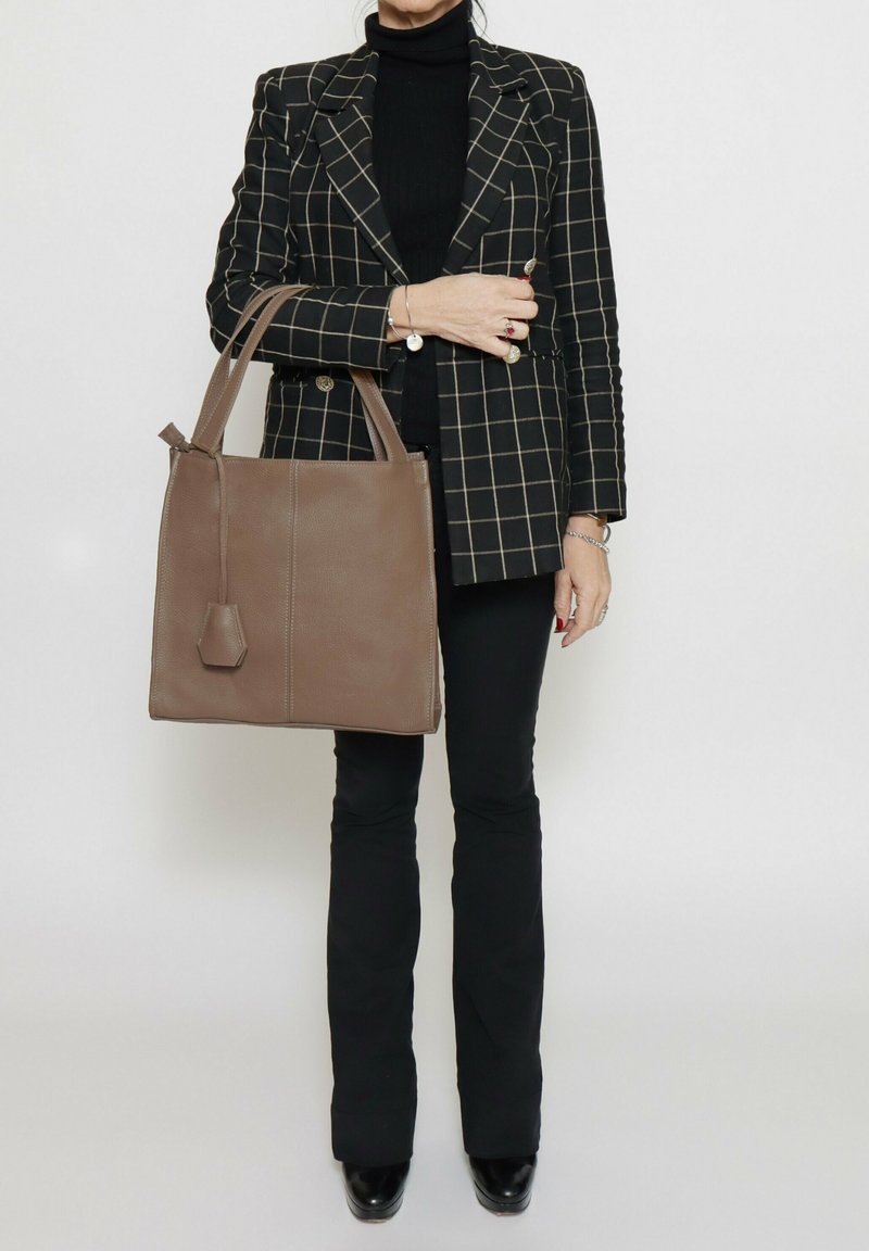 Bruine leren tote bag met een minimalistisch ontwerp, vlakke rechthoekige vorm en dubbele handgrepen. Beschikt over een gestructureerd oppervlak en subtiele hardware.