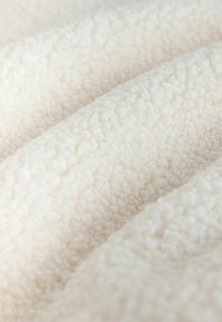 Țesătură albă texturată și plușată, cu o suprafață moale și pufoasă; bucle netede și valuri creează un aspect confortabil și o moliciune tactilă.