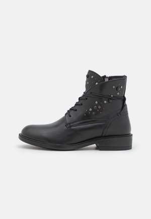 Bottine en cuir noir avec talon bas, fermeture éclair latérale, lacets à l’avant et clous métalliques décoratifs sur la partie supérieure.
