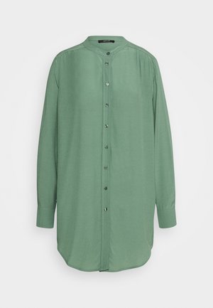 Chemise à manches longues vert clair, boutonnée, avec col mandarin et manches à poignets, présentée sur un fond uni.