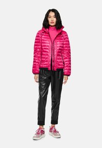 Pink puffer jacket with quilted design, zip front, and adjustable drawstring hood, paired with black leather pants and pink shoes.
