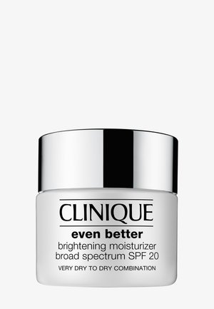Crème hydratante éclaircissante Clinique Even Better dans un pot blanc avec un couvercle argent métallique, étiquetée pour une protection à large spectre FPS 20, pour peau sèche.