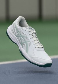 Weißer Sportschuh mit strukturiertem Obermaterial, ausgestattet mit mintgrünen Akzenten und einer gepolsterten Sohle. Schlankes Design, geeignet für den Sport.