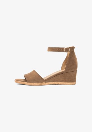 Brązowy zamszowy sandał na koturnie z paskiem wokół kostki i sprzączką, odkrytym palcem oraz plecionym detalem na krawędzi podeszwy.