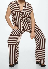 Brown and cream striped button-up shirt with short sleeves paired with matching wide-leg pants, featuring a relaxed fit and cotton texture.