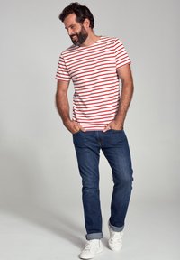 Rood-witte gestreepte t-shirt, spijkerbroek, witte sneakers. Casual outfit, met een relaxte pasvorm en zachte stof. Geen opvallende patronen of hardware.