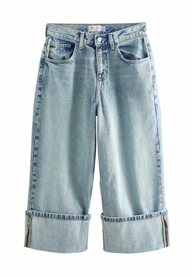Jeans de perneras anchas en azul claro, confeccionados en denim. Presentan puños enrollados, dos bolsillos frontales y un ligero desvanecimiento en el color que añade textura.