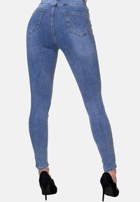 Jeans ajustados de mezclilla azul con una cintura alta, que presentan una textura suave, dos bolsillos traseros y una silueta entallada hasta los tobillos.
