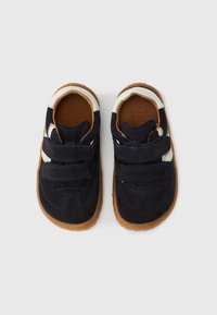 Παιδικά παπούτσια σε ναυτικό μπλε από σουέντ, με δύο λουράκια βέλκρο, σόλα από κ αουτσούκ γκαμ, και εκρού λεπτομέρεια στη φτέρνα.