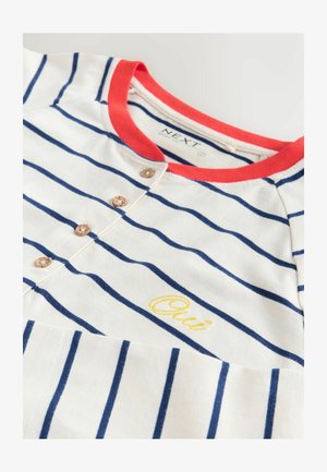 Pamut póló piros kerek nyakkal, tengerészkék és fehér csíkokkal, díszfából készült gombokkal és sárga "Oui" hímzéssel az elején.