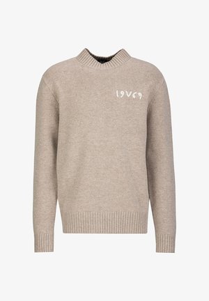 Beige sweater met een geribde zoom en manchetten. Heeft een hoge hals en "19V69" geborduurd in het wit op de voorkant. Zachte gebreide textuur.