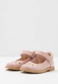 Rosa Lacklederschuhe mit abgerundeter Spitze, Ausschnitten an der Vorderseite und einem Klettverschluss für sicheren Halt. Flache beige Sohle.