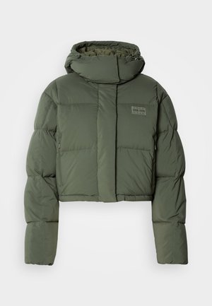 Giacca a soffietto verde oliva, cropped, con colletto alto e tasche con zip. Presenta un design trapuntato e una discreta etichetta con logo sul davanti.