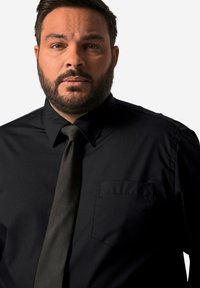 Camicia nera con un leggero luccichio, dotata di colletto a punta, una tasca sul petto e una cravatta scura abbinata. Texture liscia.