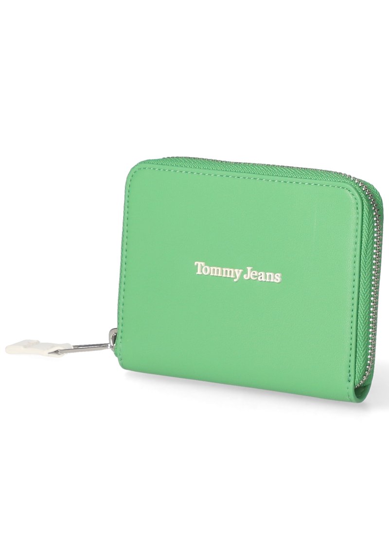 Portefeuille vert en simili cuir avec fermeture éclair, arborant un logo "Tommy Jeans" blanc à l'avant et des coutures texturées le long des bords.