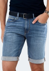 Denim shorts in light blue with a classic fit, featuring rolled hems, front pockets, and contrasting stitching. Black belt included.