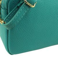 Handtas van teal leer met een gestructureerde afwerking, voorzien van gouden accenten en een verstelbare riem voor veelzijdigheid.