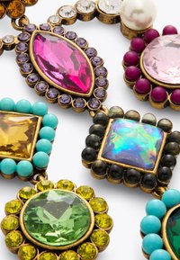 Bijoux variés ornés de pierres précieuses de différentes couleurs, dont du rose, du vert, du turquoise et des accents dorés, montés dans des designs en métal intriqués.