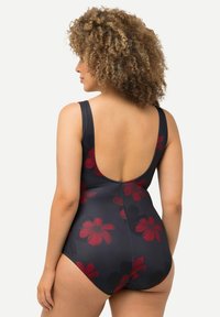 Maillot de bain une pièce bleu marine foncé avec un grand motif floral rouge ; doté de larges bretelles et d'un dos dégagé, fabriqué en tissu lisse et extensible.
