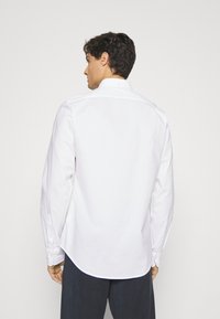 Witte overhemd met lange mouwen, voorzien van een button-down kraag, rugpand en gebogen zoom. Gemaakt van katoen met een zachte textuur.
