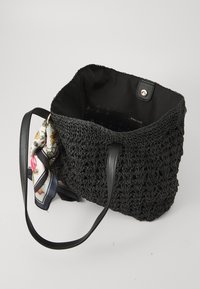 Sac à main en crochet noir avec extérieur texturé, bandoulières en cuir et accent écharpe à motif floral. Ouverture supérieure avec fermeture à pression.