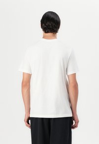 White cotton t-shirt with a crew neckline, short sleeves, and a relaxed fit. No visible patterns or logos. Smooth texture, clean design.