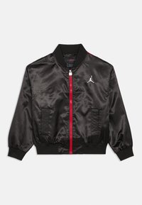 Casaco bomber em cetim preto com fecho de correr vermelho e detalhes, apresentando um colarinho canelado, punhos elásticos e um logótipo branco proeminente no peito.