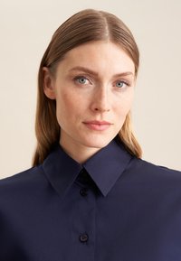 Granatowa koszula z kołnierzykiem, z guzikami z przodu i gładką fakturą, o klasycznym designie bez wzorów czy ozdób.