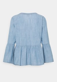 Blouse bleu clair à manches longues avec manches évasées et taille peplum. Fabriquée en tissu doux et texturé avec un léger éclat.