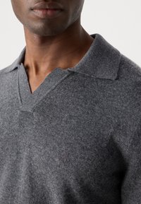 Charcoal gray pullover with a V-neck and short collar. Features a textured knit and subtle logo detail on the side.