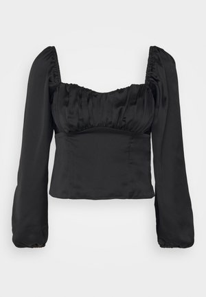 Zwarte satijnen crop top met een vierkante halslijn, geplooide buste en lange, volumineuze mouwen met elastische manchetten. Overal een gladde textuur.
