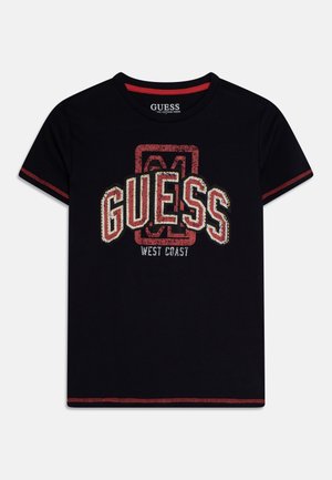 Czarny t-shirt z krótkim rękawem, czerwonym przeszyciem i dużym przetartym logo "GUESS West Coast" w kolorach czerwonym, białym i beżowym na przodzie.