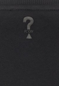 Černá žebrovaná látka s tištěným otazníkem a ikonou trojúhelníku jasnějšího odstínu. Textura je hladká a elastická.