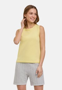 Lichtgele mouwloze top met een ronde hals, gemaakt van textuurstof, gecombineerd met grijsgestreepte shorts.