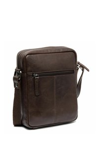 Sac à bandoulière en cuir marron avec une texture lisse, de forme rectangulaire, fermeture éclair sur le dessus et poche zippée à l'avant. Bandoulière réglable incluse.