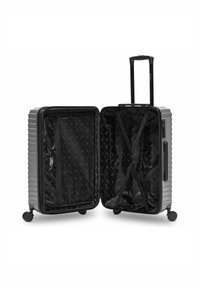 Valise rigide argentée ouverte, montrant un intérieur noir avec des sangles croisées, une poche en filet zippée, quatre roues et une poignée télescopique extensible.
