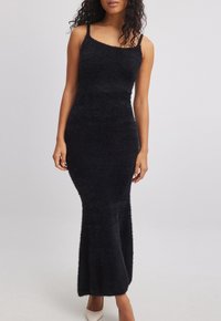 Black sleeveless maxi dress made of soft, fluffy fabric with a fitted silhouette and a slight flare at the hem. Smooth texture and simple design.