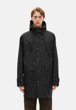 Giacca nera impermeabile con cappuccio, chiusura a bottoni, due ampie tasche frontali e polsini regolabili. Tessuto liscio e design dritto.