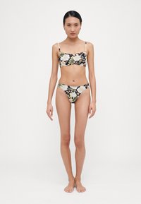Blommig bikiniuppsättning med svart bakgrund, som har en åtsittande crop top och matchande trosor. Tillverkad av slät tyg, justerbara band ingår.