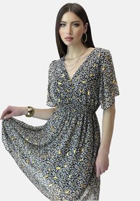 Vestido negro con estampado floral en amarillo y blanco. Hecho de tela ligera, presenta mangas cortas y una cintura elástica.