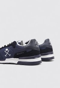 Zapatillas de deporte azul marino con acentos en blanco, que cuentan con un upper de malla suave y ante, una suela texturizada y detalles del logotipo en los paneles laterales.