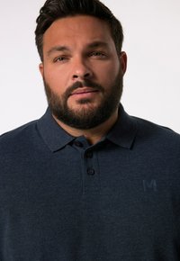 Námořnická polokošile z texturované látky s límečkem, třemi knoflíky a decentním logem "M" na hrudi. Krátké rukávy.