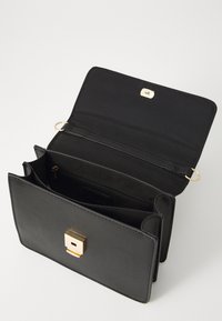 Bolso de mano de cuero negro con un cierre cuadrado dorado. Incluye un bolsillo interior con cremallera y múltiples compartimentos para la organización. Textura suave.