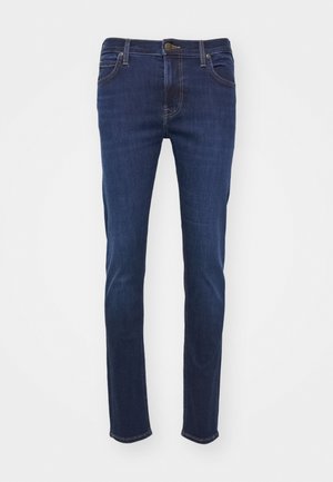 Temno modri traper hlače z ravnim krojem, ki vključujejo standardne žepe, gumbasto zapiranje in svetlo rjave kontrastne šive.