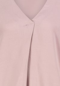 Helles pinkes Fabric mit einem V-förmigen Ausschnitt und einem kleinen sichtbaren Stich in der Mitte der vorderen Naht.