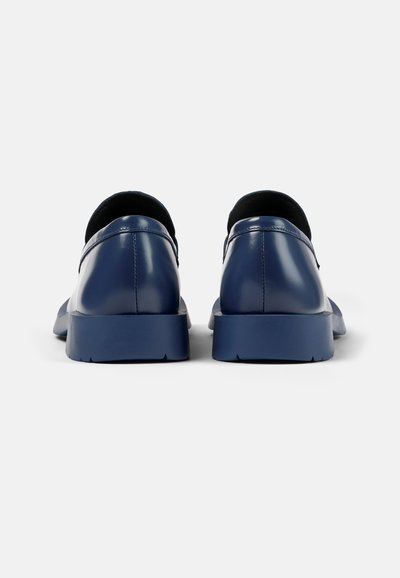 Navyblauwe leren schoenen met een gladde textuur, ronde neus en een licht verhoogde rubberen zool. De achteraanzicht toont stiksels en een gevoerd kraagje.