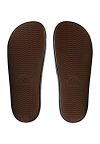 Svarta flip-flops med en texturerad brun gummisula, med ett vågigt mönster och präglad logotyp på hälen.