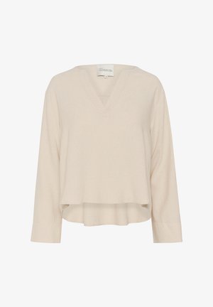 Beige, hosszú ujjú felső V-kivágással, puha tapintással és rövidített fazonnal. Oldalsó hasítékokkal a szélen a szabad mozgás érdekében.