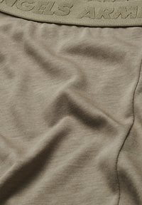 Beige fabric with a smooth texture and visible fine ribbing. Features a woven, embroidered elastic waistband with "ANGELS ARMY" text.